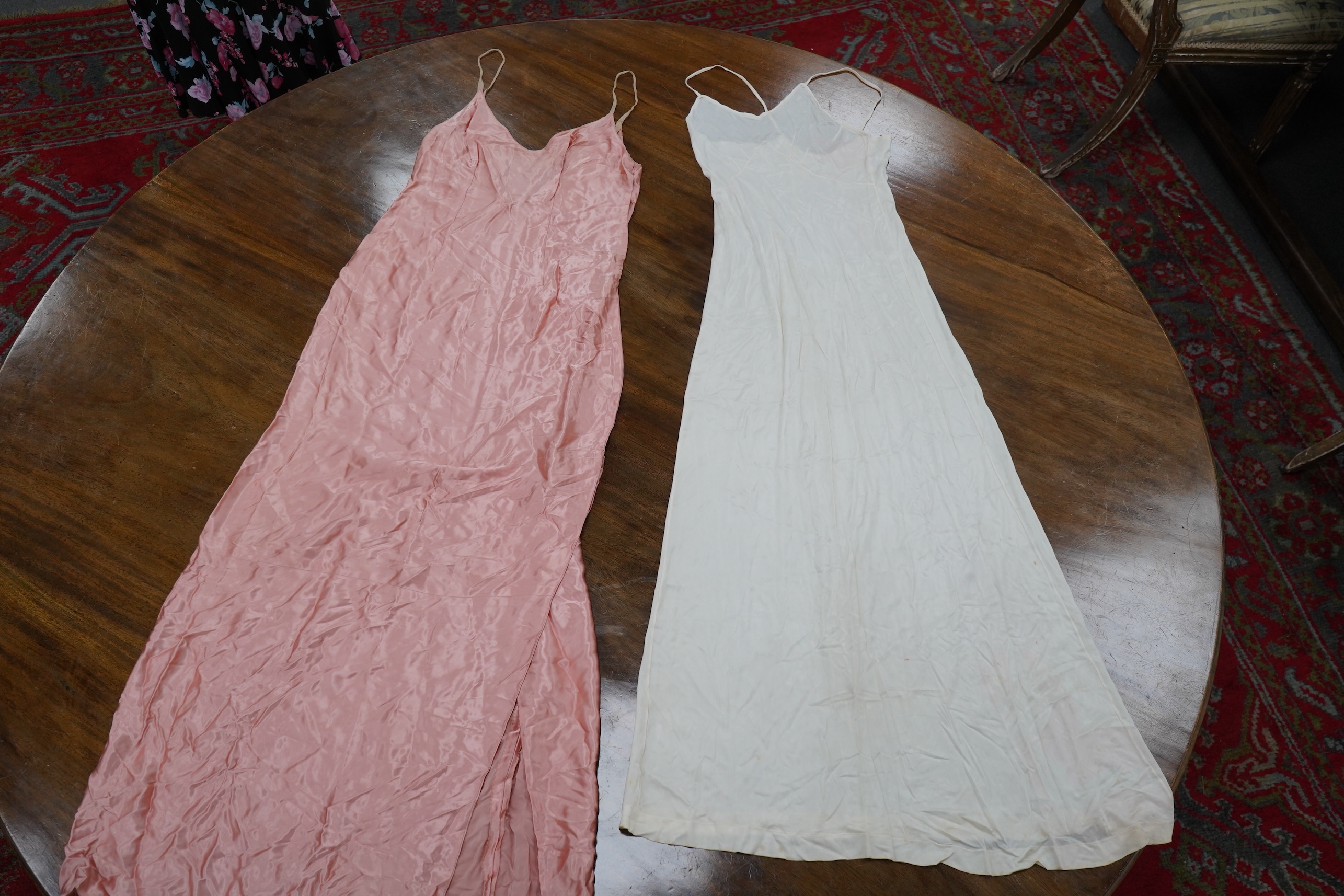 Two late 19th early 20th century long baby night gowns and two shorter baby gowns, together with a pink satin ladies full length slip and a similar cream silk stockinette slip, the bodices worked on baby dresses are embr